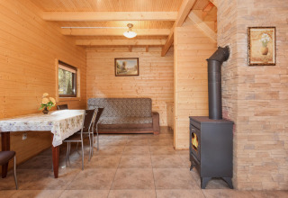 Wood-paneled living room at Holiday complex Pobierowo-Doppelhaus with sofa, dining table and stove.