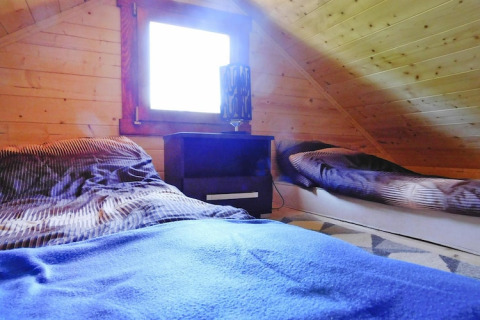 Accogliente camera mansardata in chalet a Swinoujście con due letti, comodino e pareti in legno.
