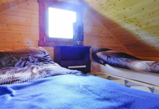 Knusse zolderkamer in houten hut in Swinoujście met twee bedden, nachtkastje en houten wanden.