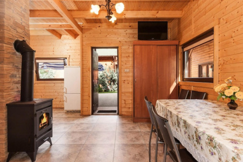 Cozy lodge interior with wooden walls, fireplace, dining table, cabinet, and view to outdoor area.