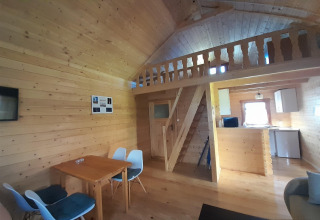 Interno in legno di casa vacanze a Swinoujście, Germania, con tavolo da pranzo, cucina e soppalco.