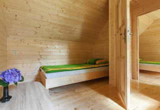 Cozy wooden bedroom at Holiday complex Pobierowo-Doppelhaus 4 and 2 with single bed, green bedding and flower.