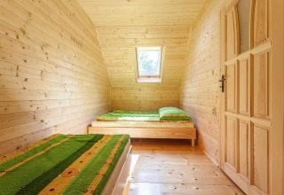 Lichte houten slaapkamer met twee eenpersoonsbedden, groene dekens en dakraam in Holiday complex Pobierowo-Doppelhaus 4 und 2.
