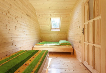 Chambre lumineuse en bois avec deux lits simples, couettes vertes et lucarne au Holiday complex Pobierowo-Doppelhaus 4 und 2.