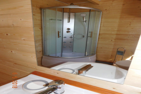 Reflejo en el espejo de una cabina de ducha moderna y lavabo en un baño de madera en Swinoujście.