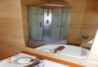 Riflesso allo specchio di una doccia moderna e lavandino in bagno con pareti in legno a Swinoujście.