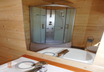 Reflejo en el espejo de una cabina de ducha moderna y lavabo en un baño de madera en Swinoujście.