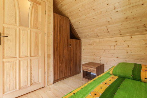 Værelse i træhytte med grøn seng, et natbord og et skab i Holiday complex Pobierowo-Doppelhaus 4 og 2, Tyskland.