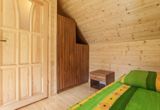 Room in a wooden lodge with a green bed, nightstand, and wardrobe at Holiday complex Pobierowo-Doppelhaus 4 and 2, Germany.