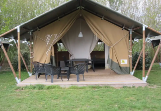 Safaritent op een houten terras bij Boerencamping Swarthoeve in Noord-Holland met tuinstoelen en tafel.