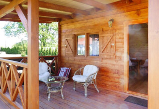 Houten veranda met stoelen en tafel bij vakantiehuis in Swinoujście voor 5 personen, gezellige sfeer.