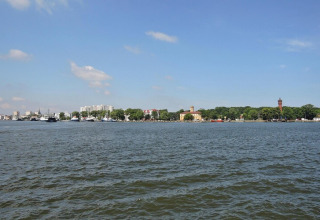 Uitzicht over het water naar gebouwen en bomen aan de oever onder een blauwe lucht in Swinoujście, Duitsland.