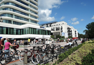 Escena urbana con edificios modernos, bicicletas y personas en Swinoujście bajo un cielo azul claro.