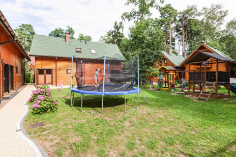 Udendørs legeplads med trampolin og legehus foran træhytter i Holiday complex Pobierowo-Doppelhaus 4 og 2.