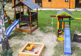 Legeplads med gynger, rutsjebaner og sandkasse foran træhytte i Holiday complex Pobierowo-Doppelhaus 4 og 2.