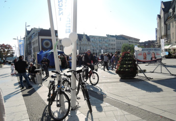 Belebter Platz in Świnoujście mit Fahrrädern, Menschen, Wahlplakaten und historischen Gebäuden.