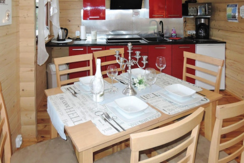 Houten vakantiewoning met gedekte eettafel voor vier, rode keuken en moderne tafeldecoratie.