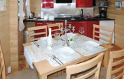 Coin repas dans un chalet en bois, table dressée pour quatre, cuisine rouge et décor raffiné.