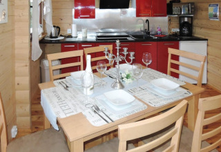Houten vakantiewoning met gedekte eettafel voor vier, rode keuken en moderne tafeldecoratie.