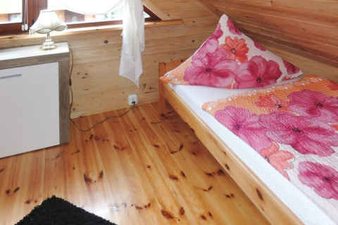 Gezellige slaapkamer in een vakantiehuis in Rewal met eenpersoonsbed, houten vloer en bloemenbeddengoed.