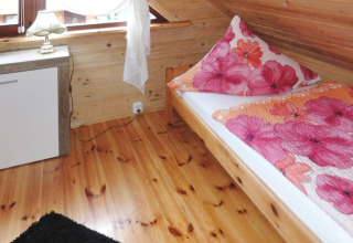 Sfeervolle slaapkamer in een vakantiewoning in Rewal met een eenpersoonsbed, houten vloer en bloemdekbed.