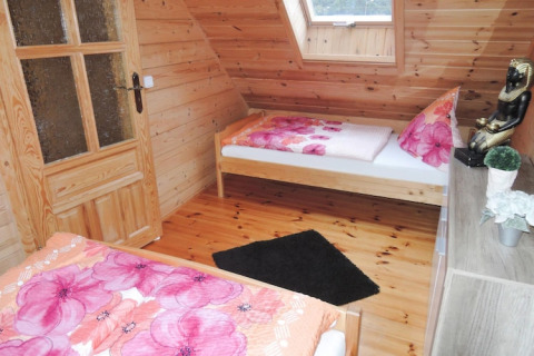 Houten slaapkamer in vakantiewoning in Rewal met twee eenpersoonsbedden en felroze beddengoed.