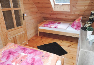 Camera in legno in casa vacanze a Rewal con due letti singoli, biancheria rosa e statua di Buddha.