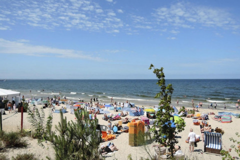Drukke strand in Rewal met veel mensen bij zee, dichtbij comfortabele vakantiehuizen voor zes personen.