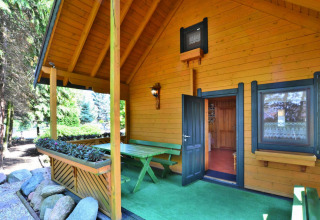Veranda coperta di casa vacanze per 6 persone a Kołobrzeg, Danimarca, con panchine verdi e piante.