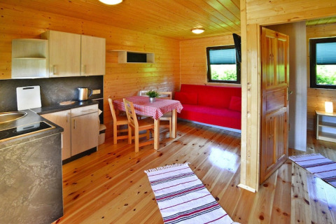 Gemütliches Sommerhaus mit Holzwänden, Küche, Essbereich, rotem Sofa und Fenstern für 4 Personen in Mielno.
