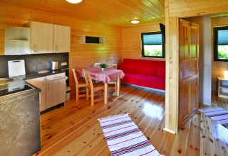 Knus houten zomerhuisje met keuken, eettafel, rode bank en ramen voor vier personen in Mielno.