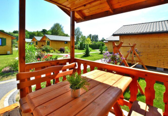 Wooden terrace with table and benches at a sunny summer cottage, surrounded by lush gardens in Mielno.