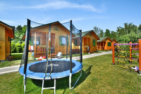 Zomerhuisjes voor 4 personen in Mielno met trampoline en speeltuin, zonnige dag en groene omgeving.