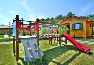 Speeltuin met glijbaan en klimrek bij een houten zomerhuisje in Mielno, omringd door groene grasvelden.