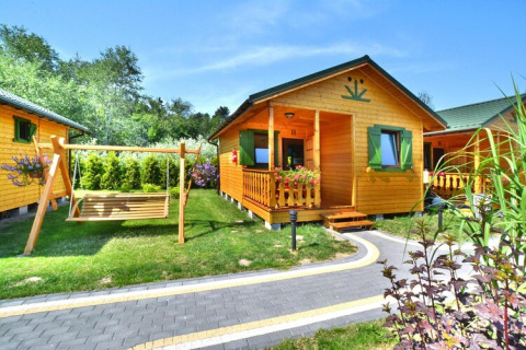 Zomerhuisje voor 4 personen in Mielno met schommel, groene tuin, veranda en houten gevel.