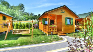 Casa estiva per 4 persone a Mielno con altalena, giardino verde, veranda invitante e facciata in legno.