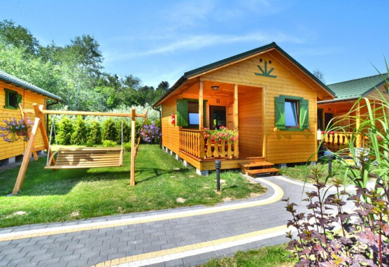 Zomerhuisje voor 4 personen in Mielno met schommel, groene tuin, veranda en houten gevel.