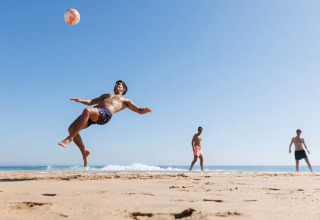 Drie mannen spelen strandvoetbal bij 'Summer cottages for 4 people Mielno' aan het strand in Denemarken.