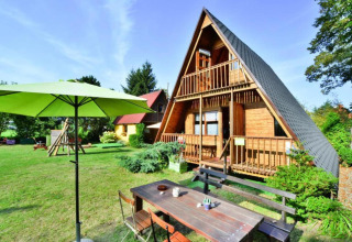 Zomerhuis TYPE B van 70 m2 in Osieki, Denemarken, met ruime tuin, tuintafel en groene parasol.