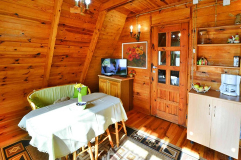 Sfeervol houten interieur van zomerhuis 70 m2 TYPE B Osieki met eettafel, zetel en kitchenette.
