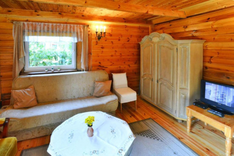 Gezellige houten woonkamer met bank, kast, tv en raam in zomerhuisje van 70m2 in Osieki, Denemarken.