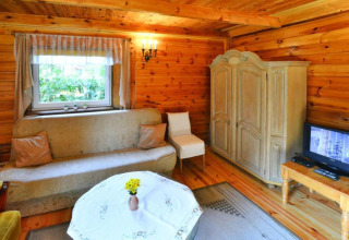 Gezellige houten woonkamer met bank, kast, tv en raam in zomerhuisje van 70m2 in Osieki, Denemarken.