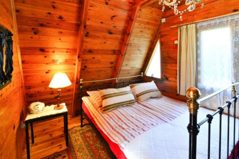 Knusse slaapkamer met houten wanden, metalen bed en raam in Summer cottage 70 m2 TYPE B Osieki.
