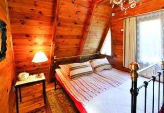 Knusse slaapkamer met houten wanden, metalen bed en raam in Summer cottage 70 m2 TYPE B Osieki.