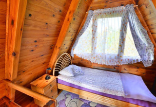 Habitación de madera con cama individual y ventana en la cabaña Summer cottage 70 m2 TYPE B Osieki, Dinamarca.