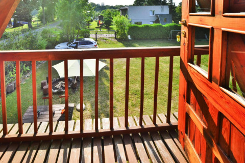 Udsigt fra altan på Sommerhus 70 m2 TYPE B Osieki i Danmark, med have, bil og picnicbord synlige.