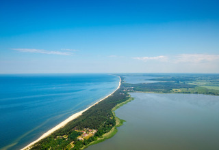 Luchtfoto van een smalle zandstrook met bos en strand bij het water, genomen bij Summer cottage 70 m2 TYPE B Osieki in Denemarken.