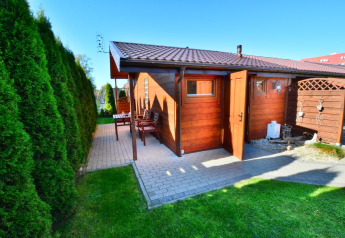 Gemütliche Holzhütte mit Terrasse und offener Tür, umgeben von Hecken bei Older year-round cottage TYPE A Ustronie Morskie.