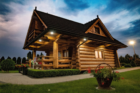 Blokhut bij Highlander cottages ZUMAR Wicie in Denemarken, omringd door tuin en bloemen in de avond.