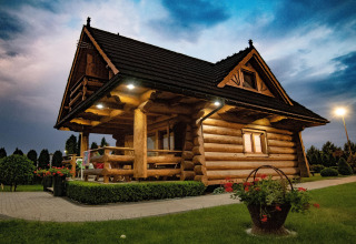 Blokhut bij Highlander cottages ZUMAR Wicie in Denemarken, omringd door tuin en bloemen in de avond.